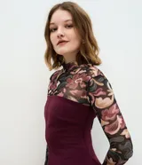 Blusa de crepé bordó sin breteles, con diseño entallado, recortes verticales y ruedo peplum con leve abertura.