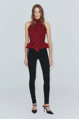 Corset bordó de cuello halter con hombros descubiertos, confeccionado con combinación de tejidos con patrón floral, detalles de volados en las sisas y bajo en peplum. Cuenta con cierre en la espalda con cremallera.