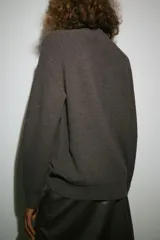 Jersey de punto color marrón chocolate con cuello subido y manga larga. Presenta un diseño de corte recto con acabados en rib en puños y ruedo.