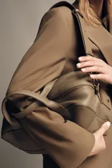 Bolso alargado tipo bowling color verde oliva, confeccionado en cuero con doble asa de mano y asa bandolera extraíble. Incluye bolsillo interior con cremallera y cierre principal con cremallera.