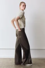 Pantalón de tiro alto confeccionado en tejido efecto piel, con diseño de pierna ancha y costuras marcadas en el delantero. Presenta cintura con trabillas, cierre frontal con cremallera, botón y gancho metálico, y bolsillos de plastrón en la espalda.