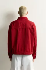 Cazadora relaxed fit de Zara confeccionada en tejido de algodón rojo con efecto lavado. Presenta cuello solapa, manga larga, bolsillos de plastrón en la cadera y cierre frontal de cremallera oculta con solapa y alamares metálicos.
