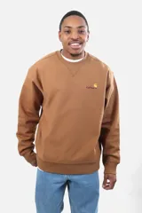 Buzo de cuello redondo Carhartt modelo American Script, color marrón tostado, con logo bordado en el pecho y detalle de costura triangular en el cuello.