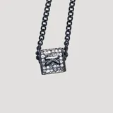Collar con dije de robot plateado cubierto de cristales brillantes y cadena de eslabones finos. El robot tiene cabeza cuadrada, cuerpo rectangular, brazos curvos y piernas rectangulares.