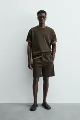 Sudadera de manga corta con cuello redondo, confeccionada en tejido texturizado de color verde oscuro/marrón. Presenta un corte relajado (relaxed fit).