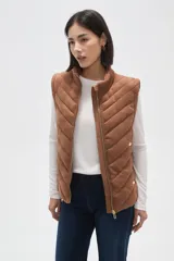 Chaleco acolchado de diseño capitoneado con cierre frontal y bolsillos laterales. Presenta un cuello alto y detalles de botones metálicos decorativos.