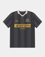 Camiseta de fútbol estilo retro de manga corta, color negro con diseño texturizado a rayas verticales, cuello en V blanco con detalle en mostaza y bordes de mangas a juego. Presenta estampados gráficos en el frente con la inscripción "PLEASURE" y emblemas deportivos.