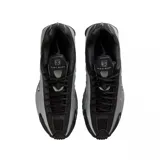 Championes Nike Shox R4 de diseño técnico en color negro total. Presentan la icónica tecnología de amortiguación Shox en el talón, con una estructura de columnas que proporciona soporte y respuesta. El exterior combina cuero sintético con paneles perforados para mayor ventilación y un acabado elegante.