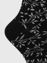 Calcetín de largo medio color negro con estampado de ramas y hojas en color gris. Presenta un borde superior con acabado ondulado.