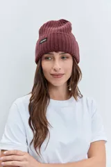 Gorro tipo beanie de punto grueso color amarillo pastel, con vuelta en el borde y etiqueta pequeña con logo en el frente.