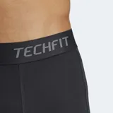 Calza deportiva Adidas Techfit de corte 3/4, color negro. Presenta cintura elástica con logo y tecnología Techfit para compresión muscular, además de inserciones de malla para mayor ventilación y tecnología Climacool que gestiona la humedad.