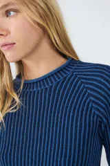 Sweater de punto acanalado color azul oscuro con rayas verticales en azul más claro. Tiene cuello redondo y mangas largas levemente acampanadas.
