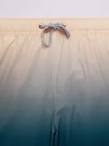 Short de baño celeste con degradado a azul marino, con cintura elástica y cordón ajustable.