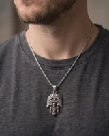 Dije de acero con diseño de mano de Fátima (Hamsa) con detalles grabados y un ojo en el centro.
