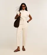 Mono largo de sarga color marrón, con cuello alto, cierre frontal con botones ocultos, sin mangas y bolsillos laterales. Incluye trabillas para cinturón.