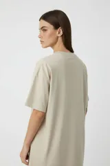 Remera de algodón de corte holgado, color beige con estampado botánico en color verde oliva y texto en el frente.