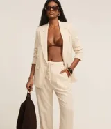 Pantalón celeste de corte recto, confeccionado en tejido de lino y viscosa. Presenta cintura elástica con lazo ajustable, bolsillos laterales y pliegues frontales.