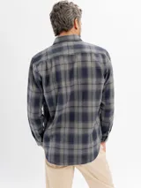 Camisa de franela a cuadros en tonos azul y negro, con cuello clásico, cierre frontal de botones y bolsillo en el pecho.