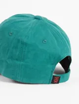 Gorra con visera curva, combinando paneles frontales y cuerpo en color verde con visera en color celeste. Presenta un bordado frontal en hilo rosado con la frase 'Breakfast, Lunch, Dinner'. Cuenta con cierre posterior regulable.