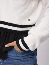 Sweater de punto estilo preppy, color blanco con detalles de rayas negras en el escote en V, puños y ruedo. De corte holgado y manga larga.