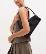 Cartera mediana de diseño rectangular con estructura rígida, confeccionada en poliuretano con textura estilo avestruz. Cuenta con dos asas fijas, cierre superior con cremallera doble y herrajes metálicos en níquel.