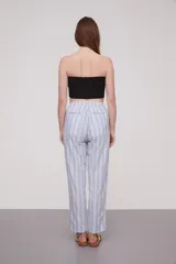 Pantalón babucha celeste con rayas verticales blancas, cintura elástica con cordón y detalle de borlas.