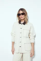 Sobrecamisa tipo Barn Jacket color marrón oscuro, de algodón con elastano, silueta relajada y estructura firme. Presenta cierre frontal con botones metálicos, cuello negro, bolsillos aplicados y pespuntes visibles.