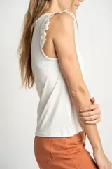 Musculosa negra de viscosa con cuello redondo y detalle de volados en los hombros. Presenta un corte holgado y fluido con un pequeño aplique metálico en el ruedo.