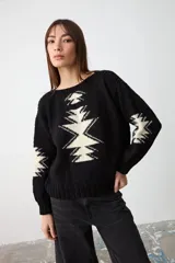 Sweater de punto negro con diseño geométrico en color crema en el frente y las mangas, de corte holgado y cuello redondo.