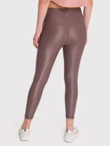 Calza deportiva de tiro alto con cintura en forma de V, confeccionada en tela brillante con acabado efecto cuero. Presenta un diseño ajustado de largo al tobillo.