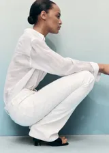 Jeans Fiona de tiro medio y corte flare con bajo deshilachado, confeccionados en tejido denim de algodón con elasticidad. Presentan diseño clásico de cinco bolsillos, trabillas para cinturón y cierre delantero con cremallera y botón metálico.