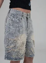 Short de jean estilo bermuda con diseño de llamas desflecadas en el frente. Presenta un lavado claro, corte recto y tiro bajo.