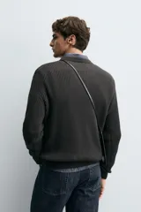 Sweater de punto en canalé color negro, de corte regular fit, cuello redondo y manga larga con terminaciones en rib.