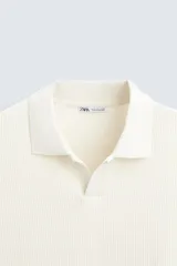 Polo de manga corta color verde oliva, con cuello solapa y abertura frontal tipo polo. Presenta una textura acanalada vertical y un calce regular.