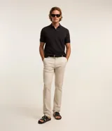 Pantalón slim de sarga color beige, de corte ajustado, con cierre frontal de botón y cremallera, y bolsillos laterales tipo cuchillo.