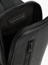 Cartera tipo sling Tommy Hilfiger de color negro, con diseño texturizado, bolsillo frontal con cierre y correa ajustable.