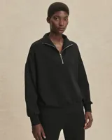 Buzo deportivo negro de corte oversize, confeccionado en tejido DoubleSoft®. Presenta cuello con paneles, media cremallera metálica y puños y bajo amplios.