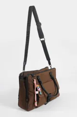Briefcase negro de nylon con tres compartimentos, dos con cierre, bolsillo delantero con solapa y cierre de broche a presión. Cuenta con doble asa de mano, correa regulable y un llavero decorativo con cuentas coloridas colgando de uno de los herrajes.