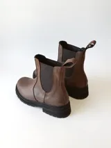 Bota tipo Chelsea de cuero color chocolate, con paneles elásticos laterales, tirador trasero y suela track negra de goma.