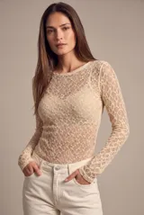 Remera de encaje color beige, de manga larga y calce al cuerpo, con cuello redondo y diseño translúcido.