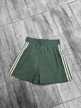 Short deportivo verde con cintura elástica ajustable con cordón y tres rayas blancas a los costados.