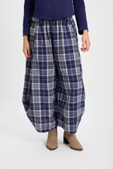 Pantalón de corte holgado con silueta tipo balloon, confeccionado en tela a cuadros. Presenta cintura elástica con cordón ajustable y cortes laterales circulares que aportan volumen a la prenda.