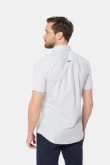 Camisa lisa de manga corta color crema, confeccionada en 100% algodón, con cuello abotonado y un bolsillo en el pecho.