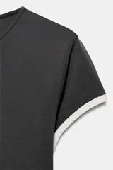 Camiseta de corte slim fit, color verde militar, con cuello redondo y manga corta. Presenta vivos de contraste blancos en el ruedo de las mangas y en el bajo.