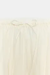 Falda midi fluida de tiro medio, color blanco, con cintura elástica ajustable mediante cordones y bajo asimétrico.