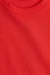 Remera roja de manga corta confeccionada en punto de algodón tupido, con cuello redondo ribeteado y acanalado.