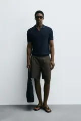 Polo de manga corta, color celeste pálido, con cuello solapa y abertura frontal en V. Tejido de punto con textura acanalada vertical.