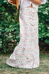 Falda larga de algodón con estampado floral, tiro alto y cierre frontal con botones de madera. Presenta un diseño evasé con un volante en el bajo.