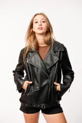 Chaqueta negra de eco-cuero, corte recto y oversize, con solapas amplias, múltiples bolsillos y cierres en las mangas.