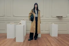 Trench color beige con cuello camisero, doble botonadura frontal, cinturón y bolsillos laterales.